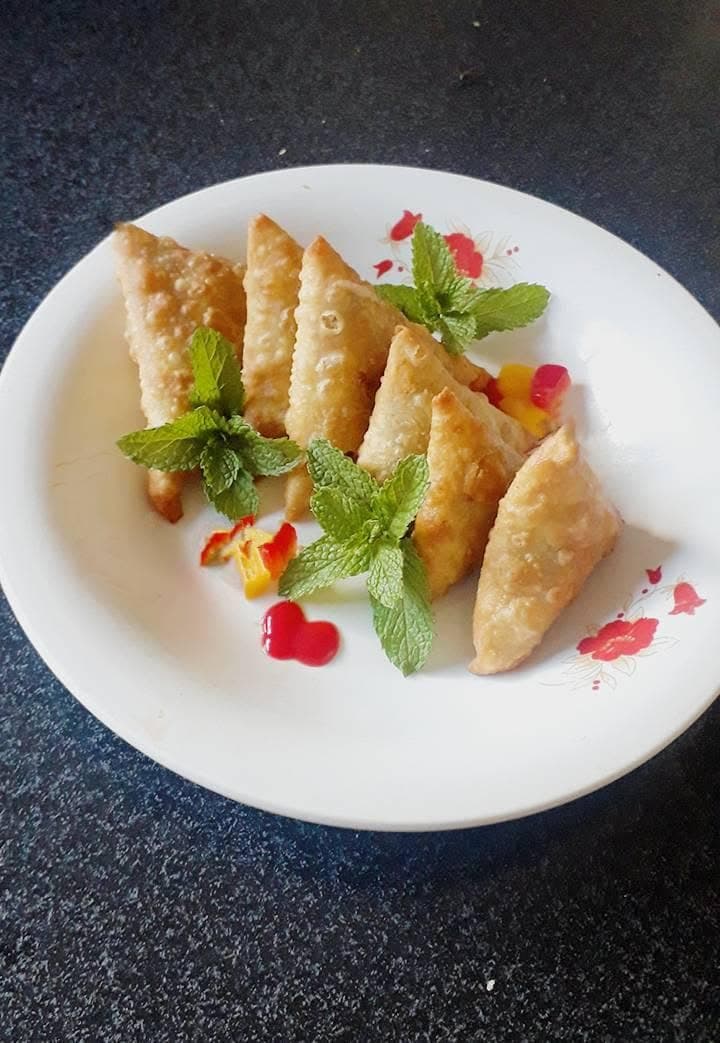 Plated savoury samosas with fresh garnish and dipping sauce