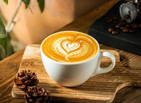 Freshly prepared latte on a warm wooden café table